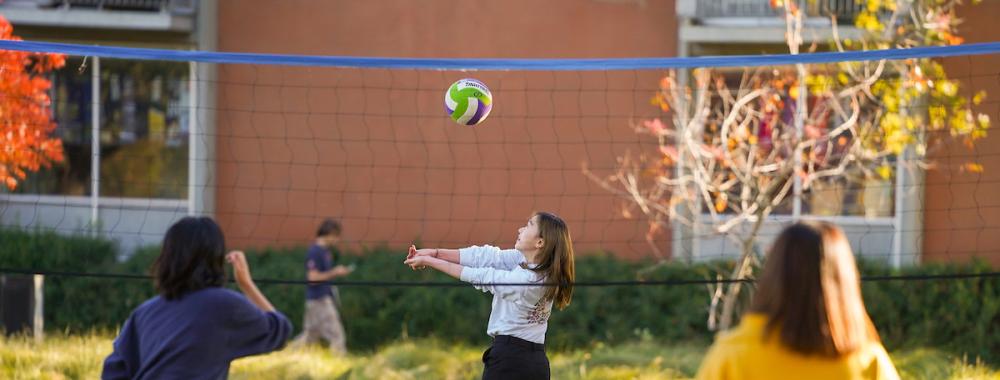 Students play volleyball in front of the International Center