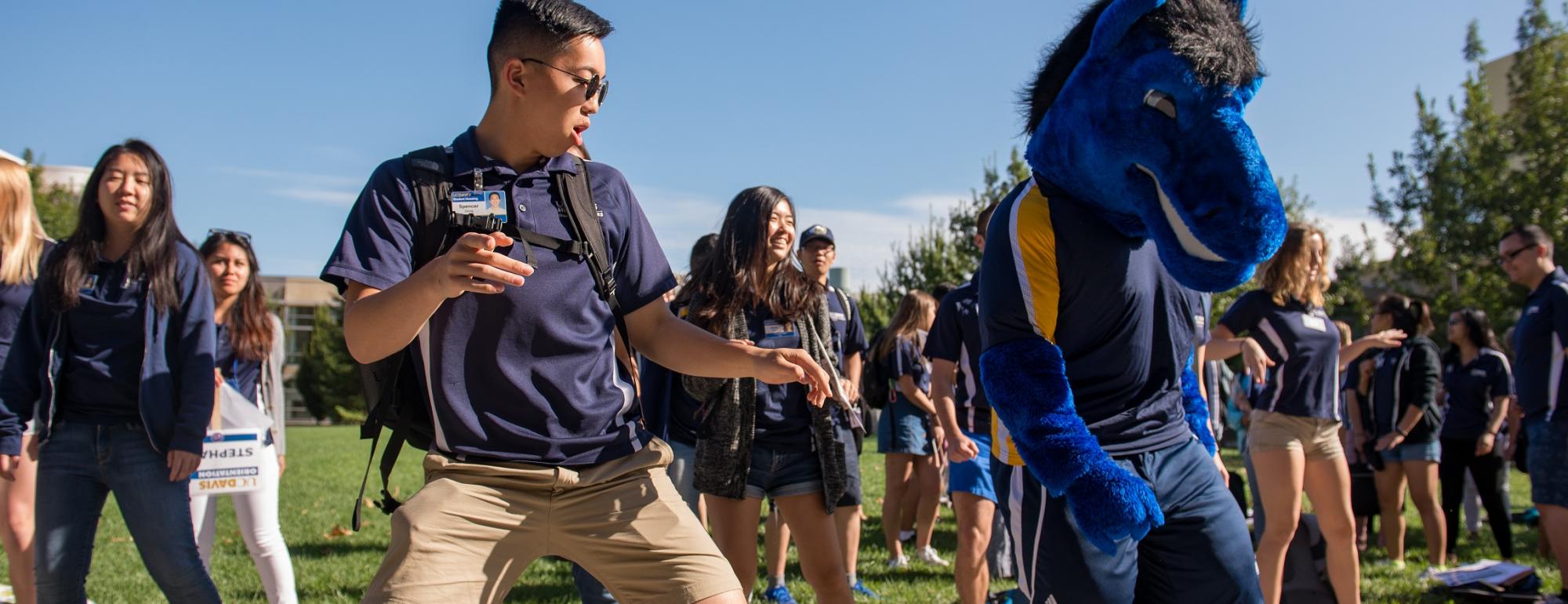 Orientation Leader dancing outside with Gunrock, the UC Davis mascot.